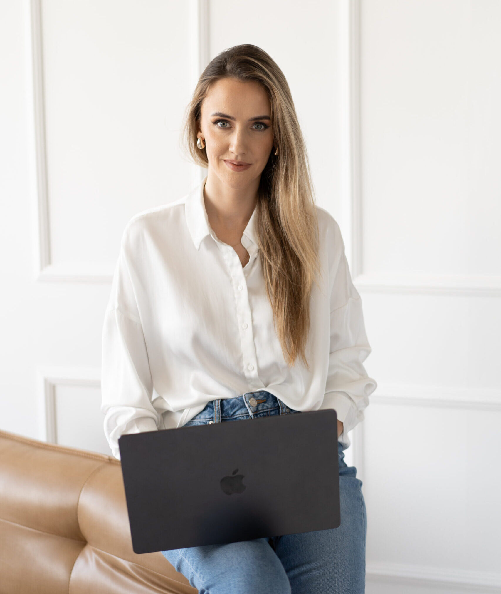 Dagmara Grzeszczuk z The Sparkling Media od marketingu dla architektów opiera się o brązowy fotel.