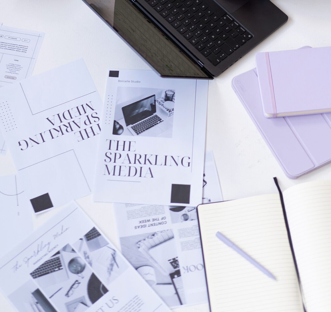 Leżące na ziemi kartki z logo i grafikami firmy The Sparkling Media.