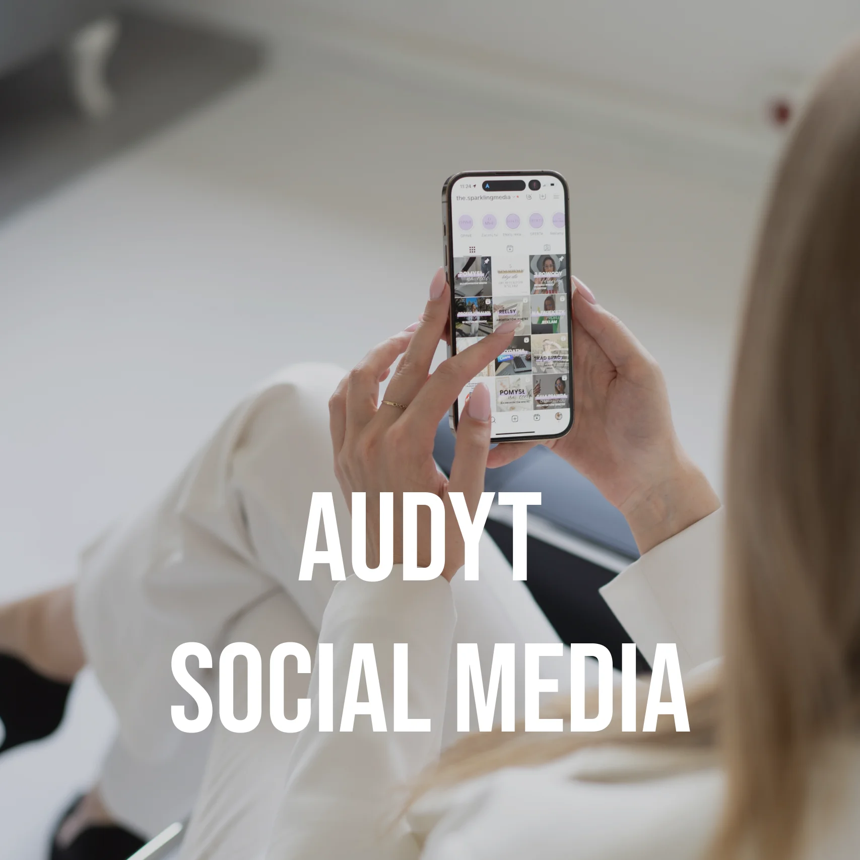 Aagmara Grzeszczuk z The Sparkling Media od marketingu dla architektów siedzi na czarnym metalowym krześle i w dłoniach trzyma smartfona. Na środku biały napis "AUDYT SOCIAL MEDIA".